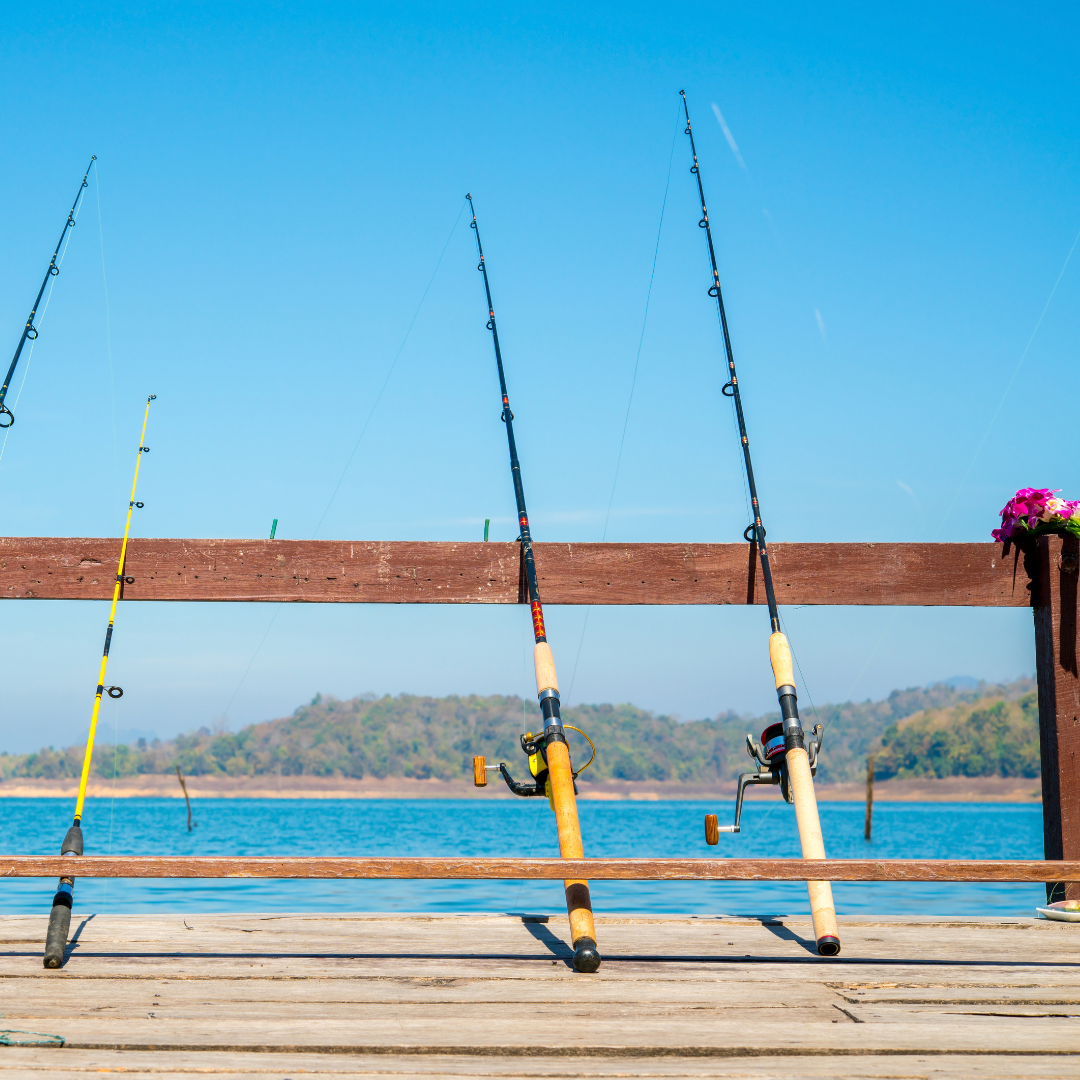 fishing poles leaning against a fence in front of a lake